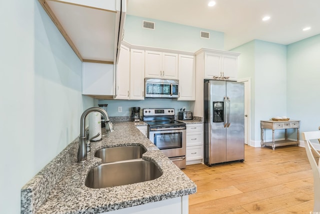 kitchen with white cabinets, light stone countertops, light hardwood / wood-style flooring, sink, and stainless steel appliances