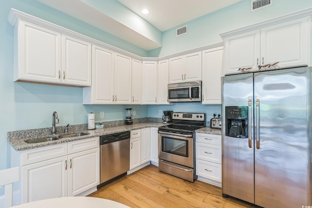 kitchen featuring sink, light hardwood / wood-style floors, stainless steel appliances, white cabinets, and light stone counters