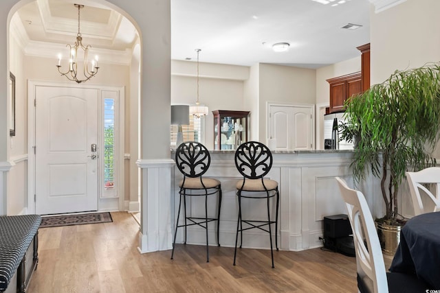 foyer entrance featuring a notable chandelier, ornamental molding, and light hardwood / wood-style flooring