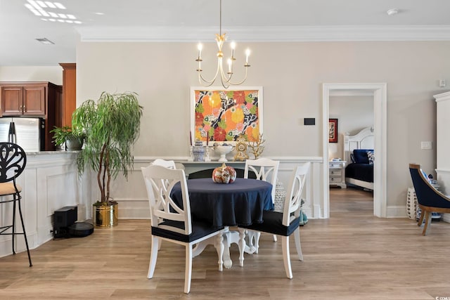 dining space featuring ornamental molding, light hardwood / wood-style flooring, and a notable chandelier