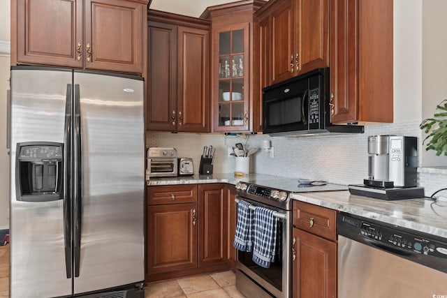 kitchen featuring stainless steel appliances, light stone counters, and backsplash