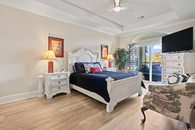 bedroom with access to exterior, light hardwood / wood-style flooring, a tray ceiling, ornamental molding, and ceiling fan