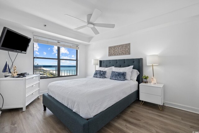 bedroom with a water view, ceiling fan, and dark wood-type flooring