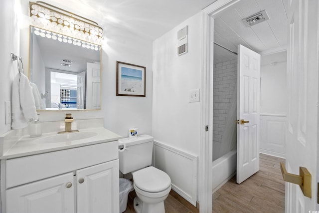 full bathroom featuring toilet, hardwood / wood-style floors, tiled shower / bath combo, and vanity