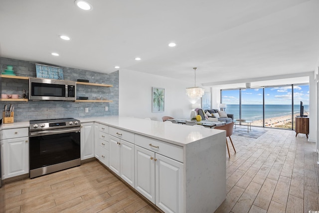 kitchen featuring a water view, white cabinetry, kitchen peninsula, and stainless steel appliances