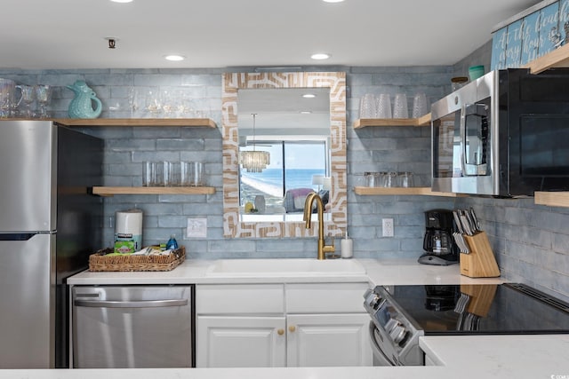 kitchen featuring white cabinetry, backsplash, appliances with stainless steel finishes, and sink