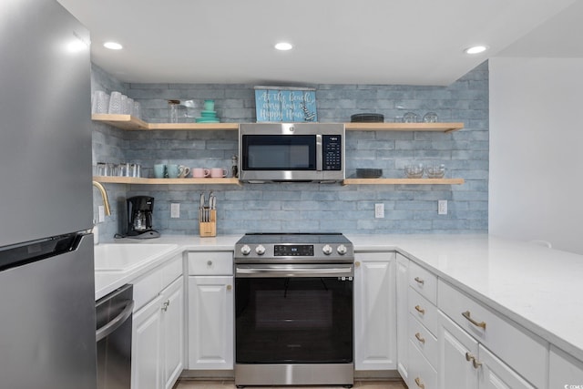 kitchen with decorative backsplash, white cabinets, and stainless steel appliances