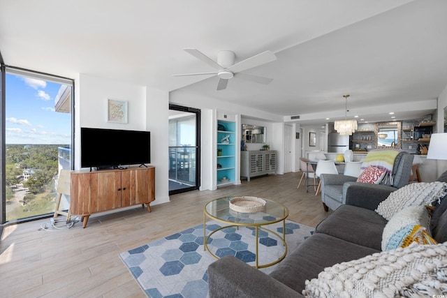 living room featuring light hardwood / wood-style flooring and ceiling fan with notable chandelier