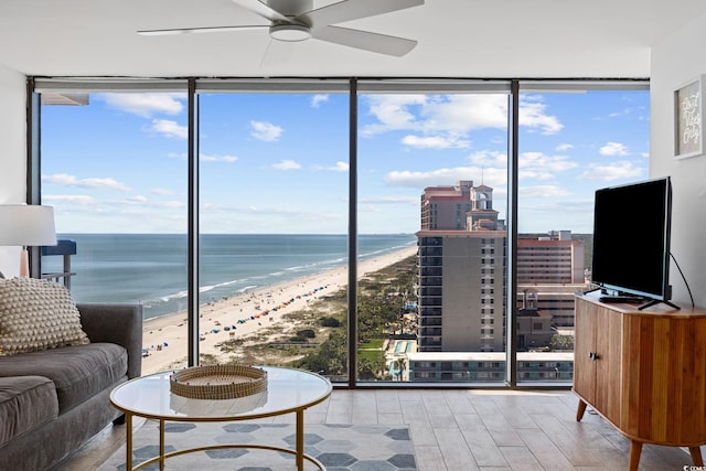 interior space featuring expansive windows, ceiling fan, a water view, and hardwood / wood-style flooring