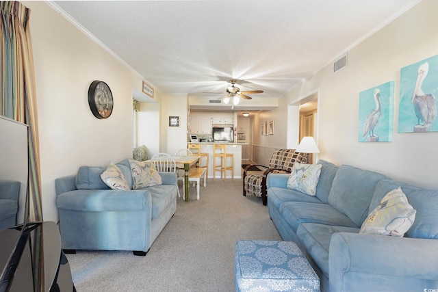 carpeted living room with crown molding, ceiling fan, and a textured ceiling