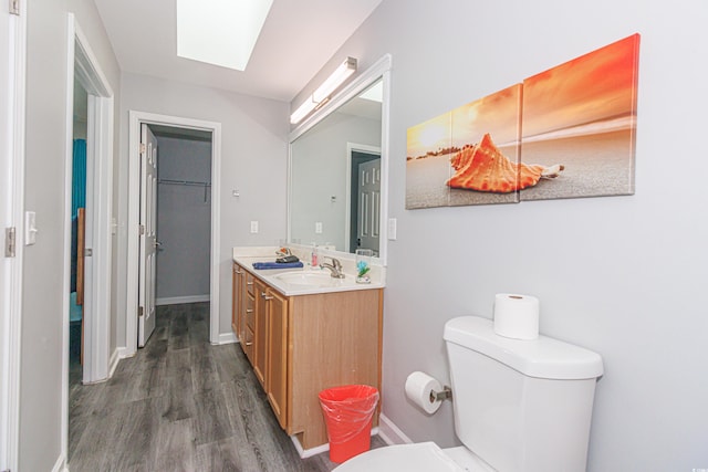 bathroom featuring vanity, hardwood / wood-style floors, toilet, and a skylight