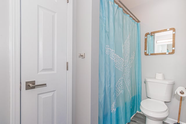 bathroom featuring toilet, wood-type flooring, and curtained shower