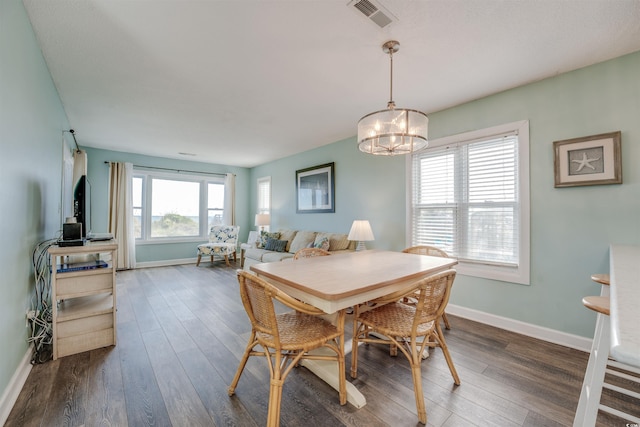 dining area with a notable chandelier, a wealth of natural light, and dark hardwood / wood-style flooring