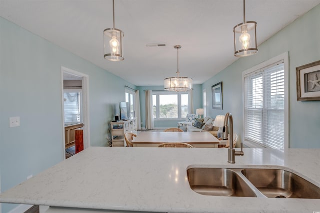 kitchen featuring plenty of natural light, open floor plan, light stone counters, and a sink