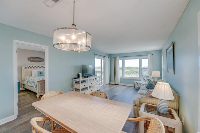 dining space featuring an inviting chandelier, wood finished floors, visible vents, and baseboards