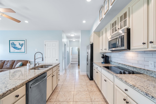 kitchen with tasteful backsplash, light stone countertops, appliances with stainless steel finishes, sink, and light tile patterned floors