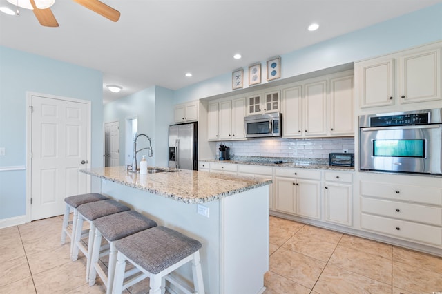 kitchen featuring backsplash, a kitchen breakfast bar, an island with sink, sink, and stainless steel appliances