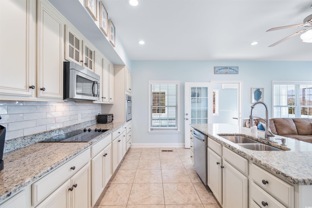 kitchen with a healthy amount of sunlight, sink, light stone counters, and stainless steel appliances