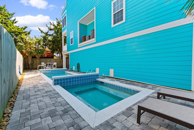 view of swimming pool featuring a patio area and an in ground hot tub