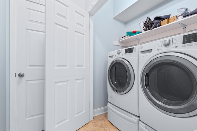 laundry area featuring washer and dryer, ornamental molding, and light tile patterned floors