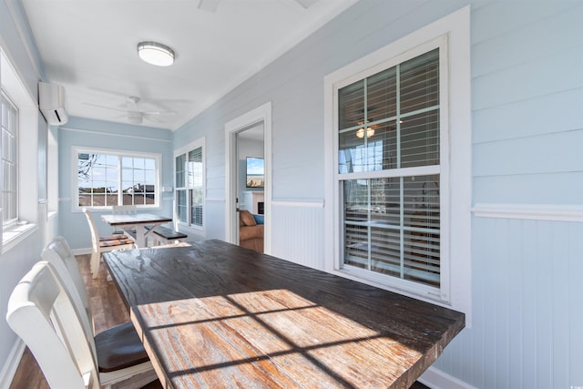 sunroom with a wall unit AC and ceiling fan