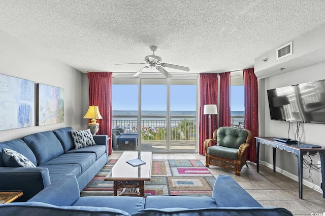 tiled living room with a wall of windows, a textured ceiling, and ceiling fan