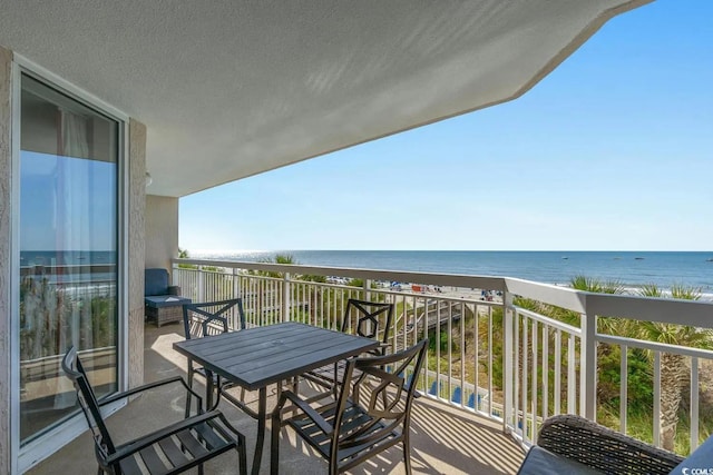 balcony with a water view and a view of the beach