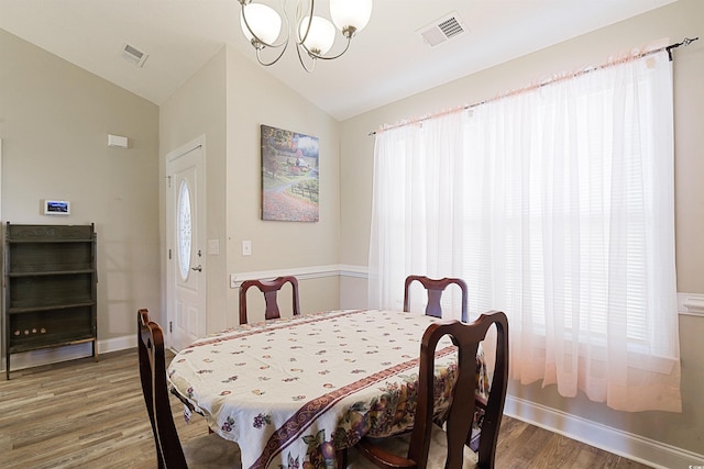 dining room featuring hardwood / wood-style floors, lofted ceiling, and a chandelier