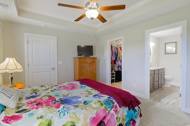 bedroom featuring a tray ceiling, ensuite bath, a spacious closet, and ceiling fan