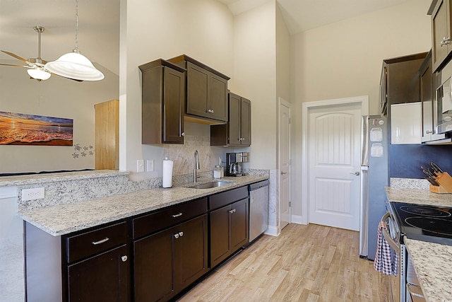 kitchen featuring dark brown cabinetry, stainless steel appliances, sink, high vaulted ceiling, and light hardwood / wood-style floors