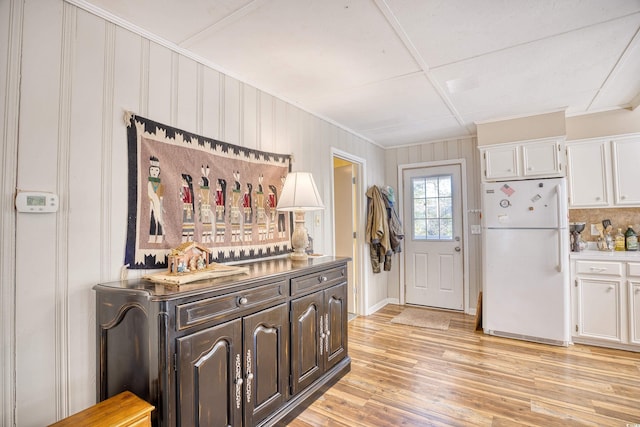 kitchen with white cabinets, dark brown cabinetry, white fridge, and light wood-type flooring