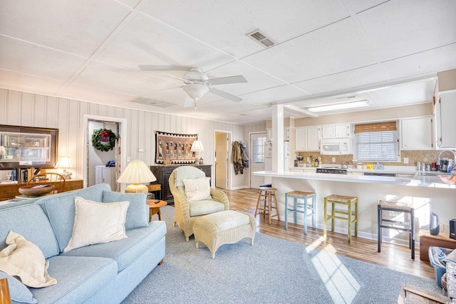 living room with ceiling fan, sink, and light wood-type flooring