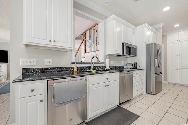 kitchen featuring stainless steel appliances, dark stone countertops, ornamental molding, sink, and white cabinetry