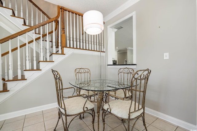 dining space featuring a textured ceiling, ornamental molding, and light tile patterned floors