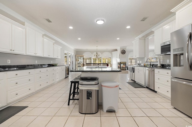 kitchen with a breakfast bar, appliances with stainless steel finishes, crown molding, and white cabinetry