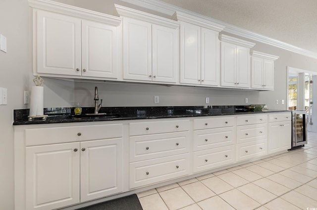 kitchen with sink, white cabinets, dark stone countertops, wine cooler, and light tile patterned floors