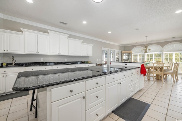 kitchen with black electric stovetop, white cabinetry, sink, and a wealth of natural light