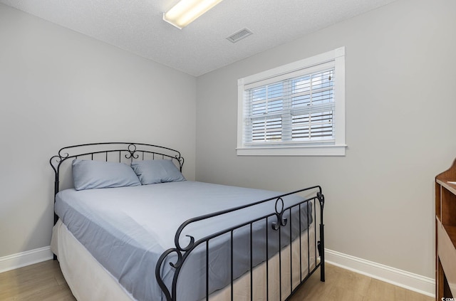 bedroom featuring light hardwood / wood-style flooring and a textured ceiling