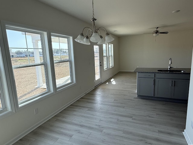 unfurnished dining area with sink, a notable chandelier, and light hardwood / wood-style floors