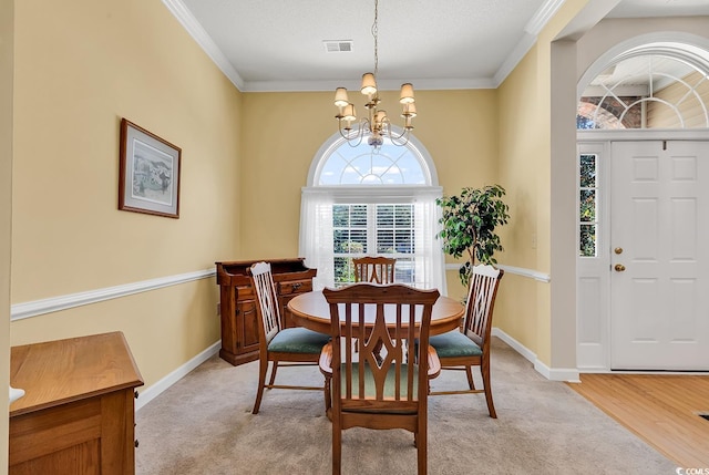 dining space with crown molding, a notable chandelier, a textured ceiling, and light hardwood / wood-style floors