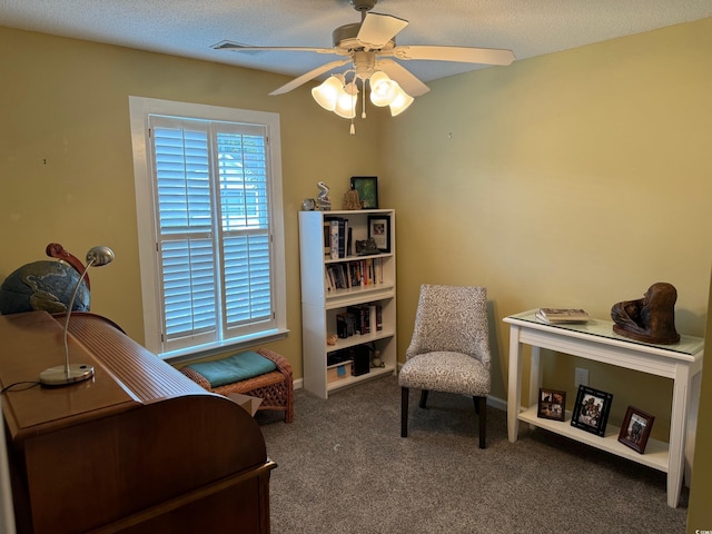 living area featuring carpet floors, a textured ceiling, and ceiling fan