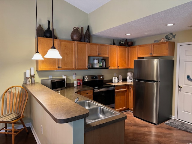 kitchen featuring sink, dark hardwood / wood-style flooring, kitchen peninsula, stainless steel appliances, and decorative light fixtures