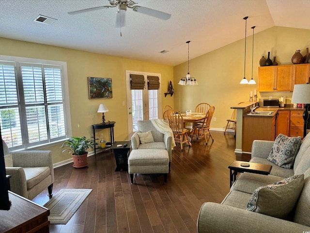 living room with dark wood-type flooring, lofted ceiling, plenty of natural light, and ceiling fan with notable chandelier