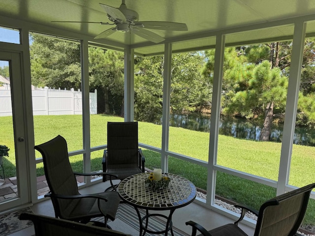 sunroom / solarium featuring a water view and ceiling fan