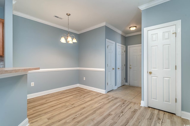 unfurnished dining area with visible vents, ornamental molding, light wood-style floors, baseboards, and a chandelier