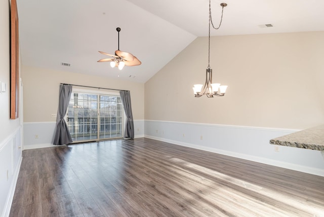 spare room with ceiling fan with notable chandelier, dark hardwood / wood-style flooring, and vaulted ceiling