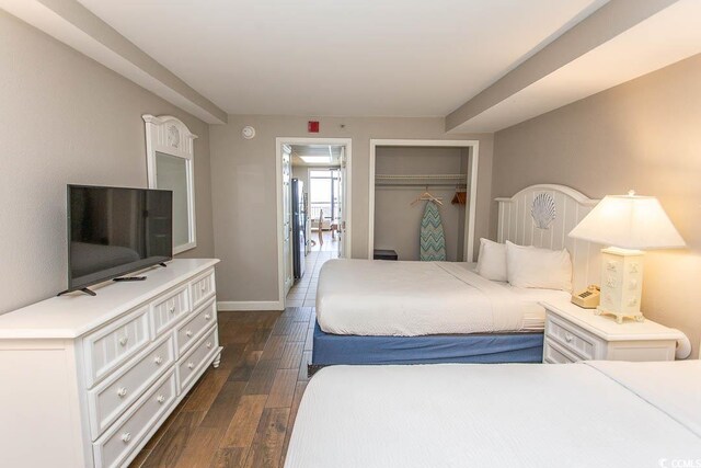 bedroom with dark wood-type flooring, a closet, and stainless steel fridge