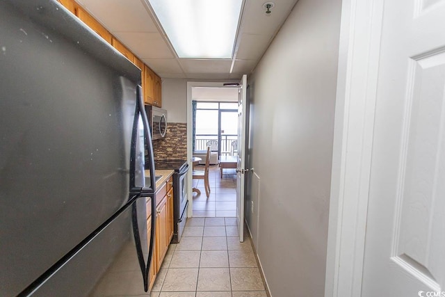 kitchen with a drop ceiling, stainless steel appliances, and light tile patterned floors