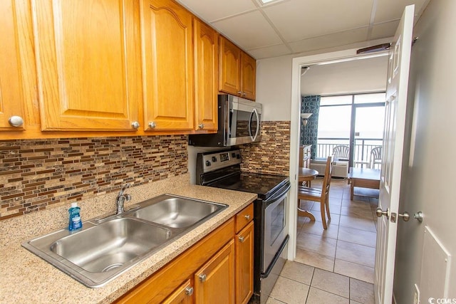 kitchen with backsplash, sink, light tile patterned floors, appliances with stainless steel finishes, and a paneled ceiling