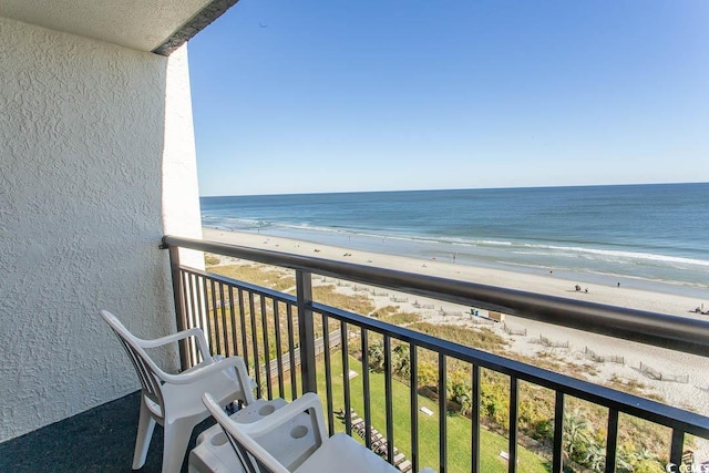 balcony with a water view and a view of the beach